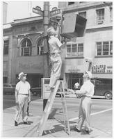Sanford Smith and two other men installing a pedestrian crossing signal at the intersection of Elm and Market streets